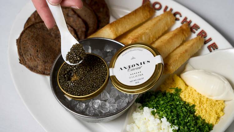 A hand scooping caviar out of a tin