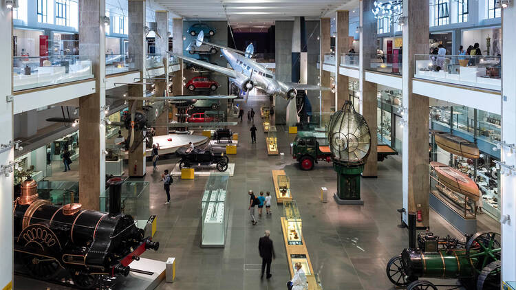 Inside large room at Science Museum with cars and plans