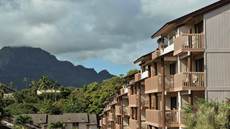 Exterior of Banyan Harbor Resort with Kauai Mountains in the distance.