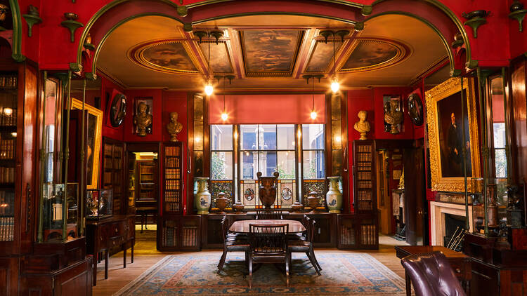 Inside a grand room painted red with paintings hung on the wall 