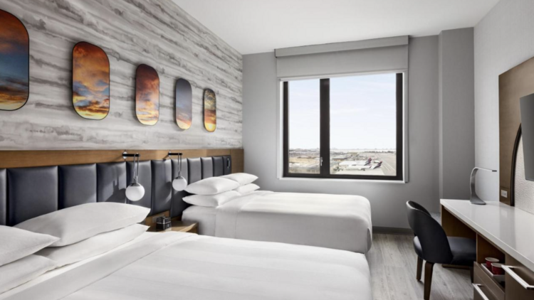 an JFK airport hotel room with two beds and airport views