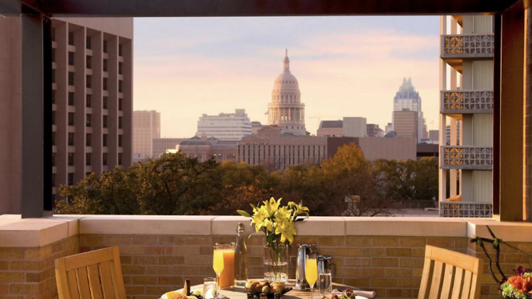 Balcony with a set dining table with two chairs overlooking views of the city.