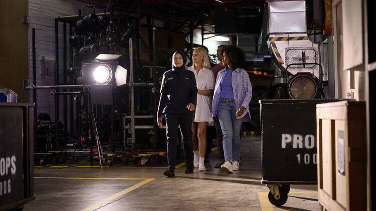 Three people walking around backstage of Opera House 