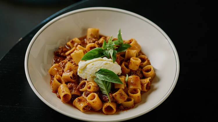 A bowl of tubetoni bolognese with basil and cheese.