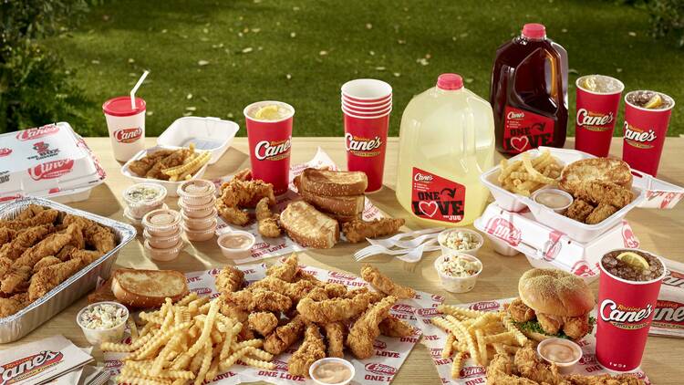 a table of Raising Cane's fried chicken, fries and other food