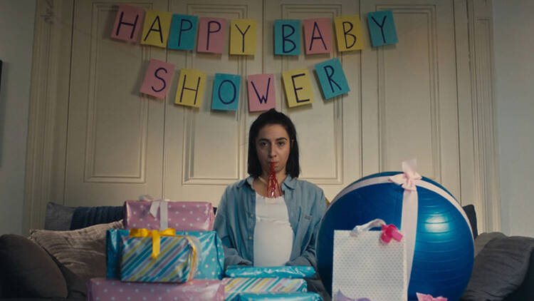 A woman sitting in front of gifts at a baby shower