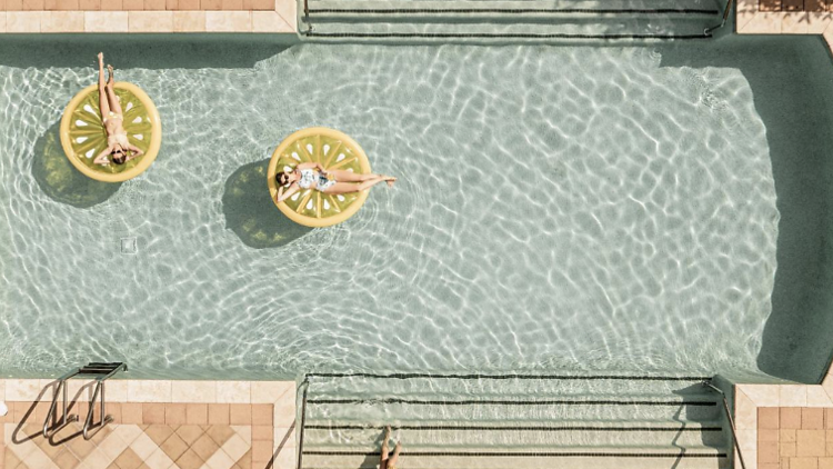 Aerial view of people floating in hotel Viata's outdoor pool. 