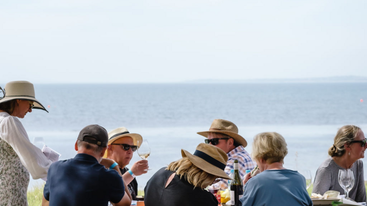 People enjoying a wine tasting by the sea. 