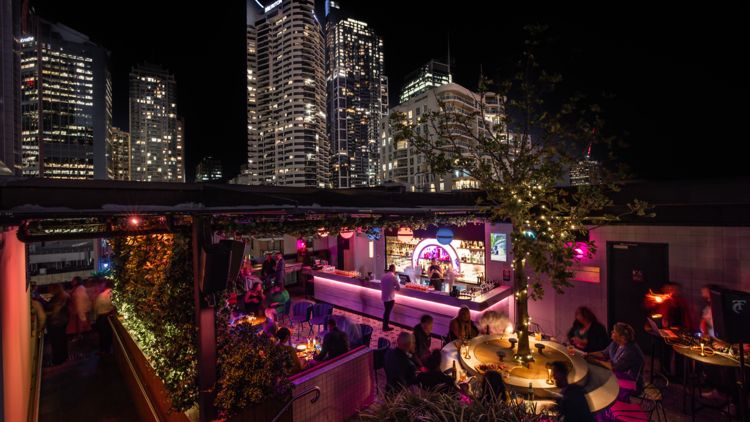 Aerial shot of bar at night time with views of lit-up skyscrapers
