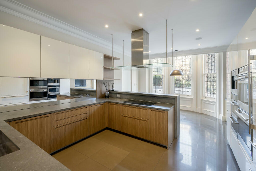 A bright, modern kitchen with steel light fixtures and light wooden cabinets 