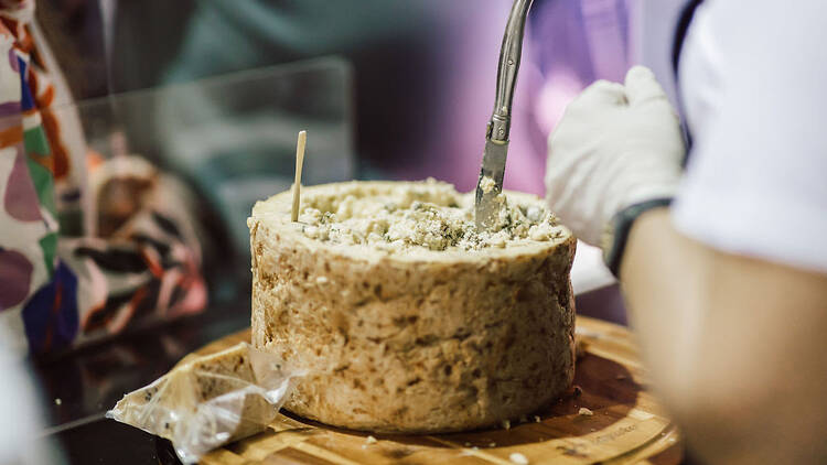 Wheel of cheese with a knife in it.