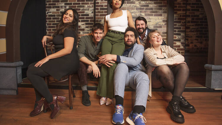 The Second City cast poses on stage.