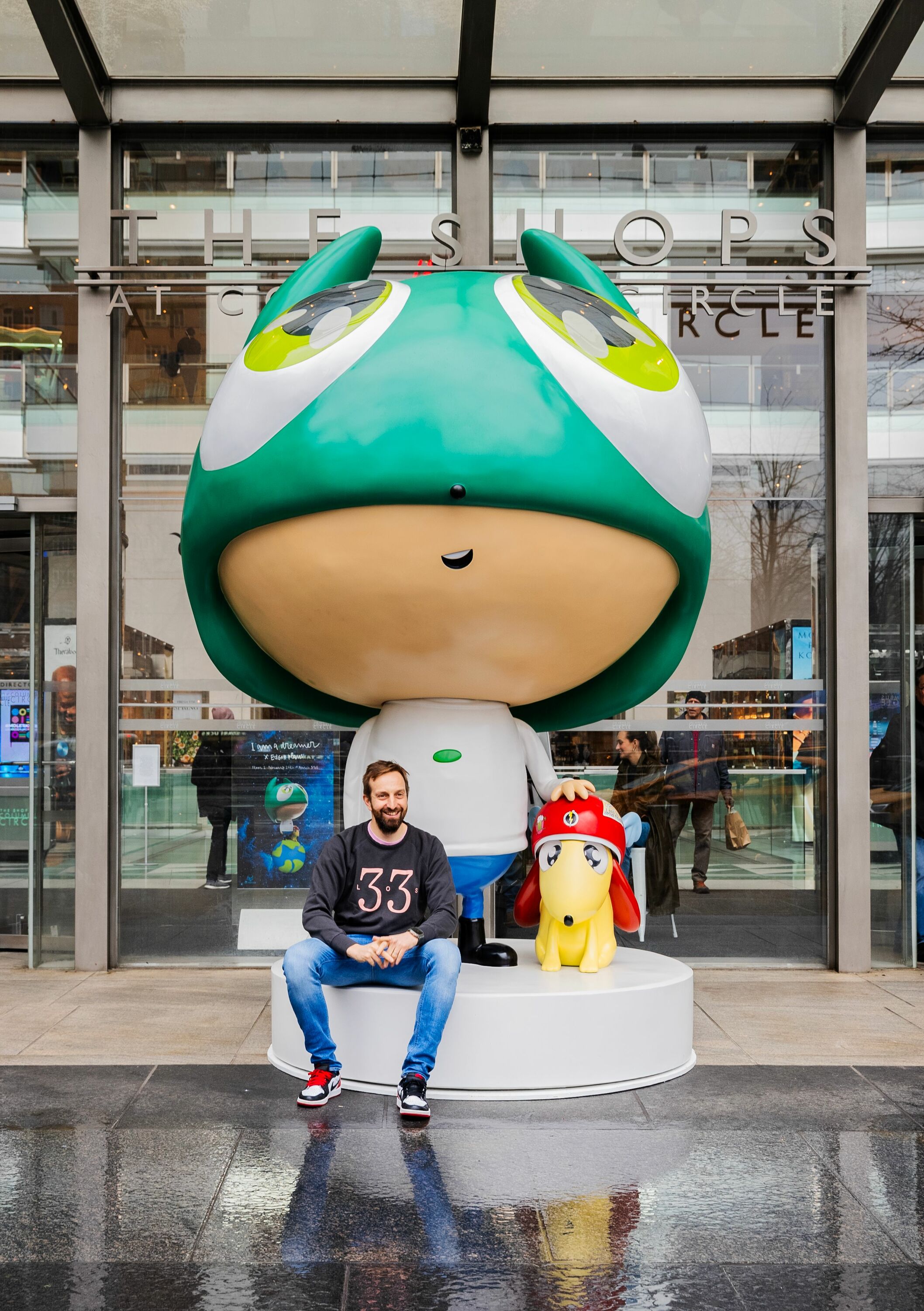 man sits in front of giant scultpure