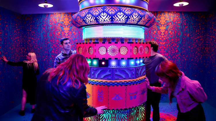 Visitors interact with a joy neon glowing joy generator