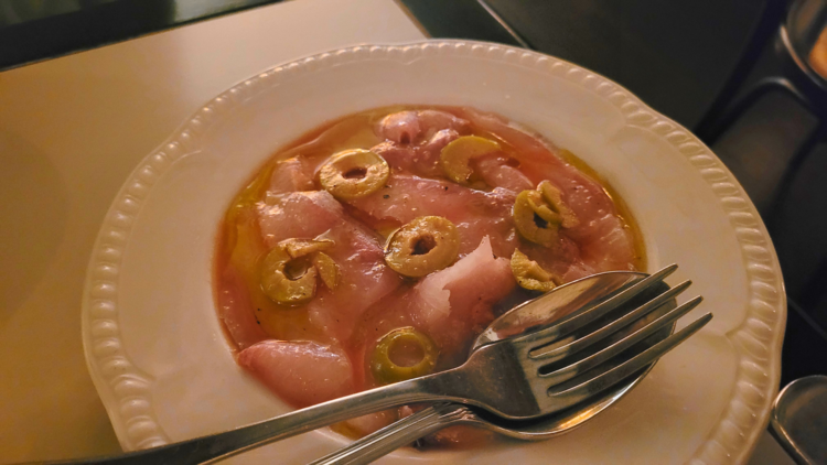 A plate of raw kingfish with sliced green olives