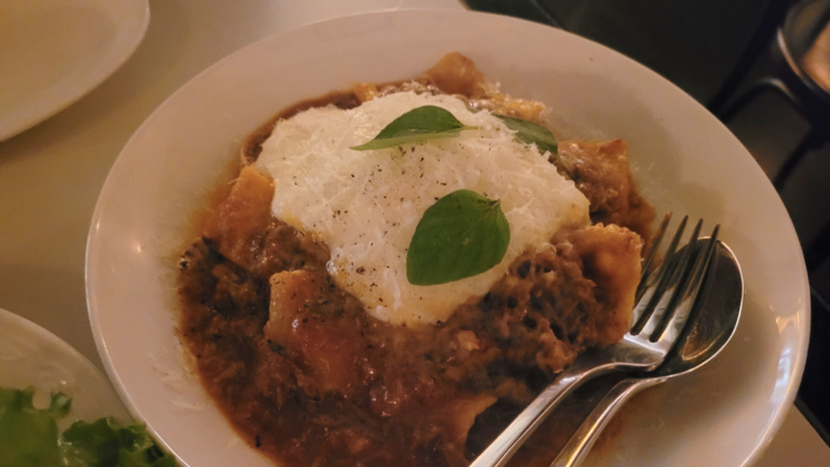 A bowl of pasta with a beef ragu, topped with creamy sauce