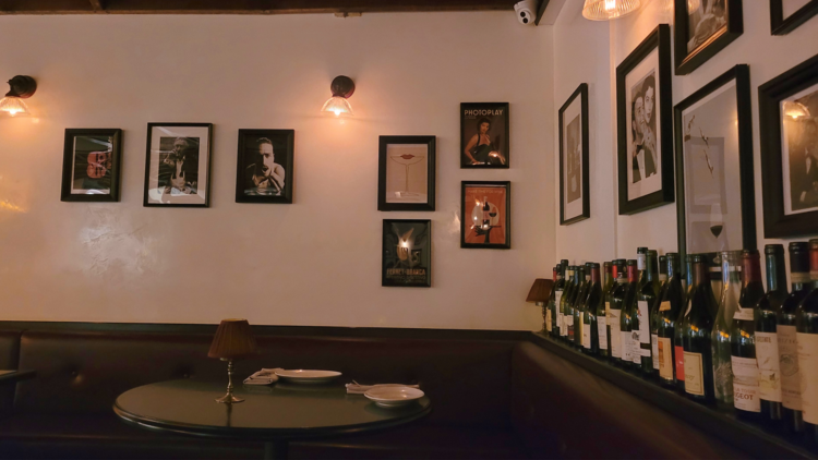 A restaurant with bottles of wine along the wall and lots of framed pictures.