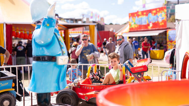 A boy in a racer car as part of a carnival ride