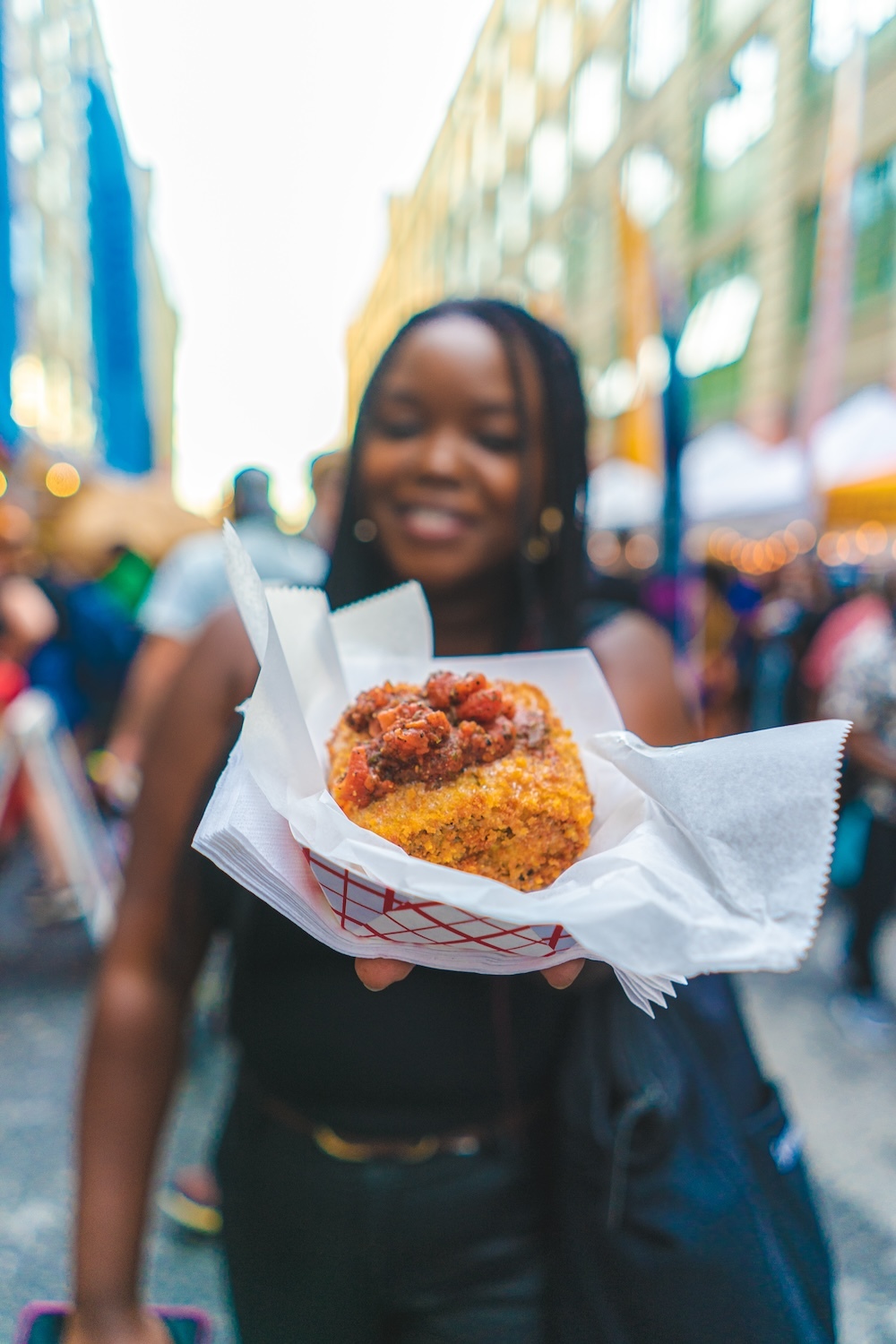 A person holds a food item towards the camera at a market