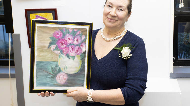 a person holds up a painting of flowers