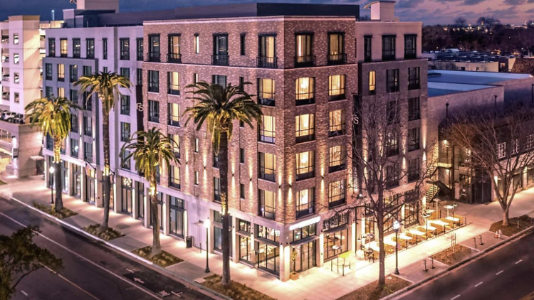 Exterior tower of Fort Sutter Hotel Sacramento lit up at night time.