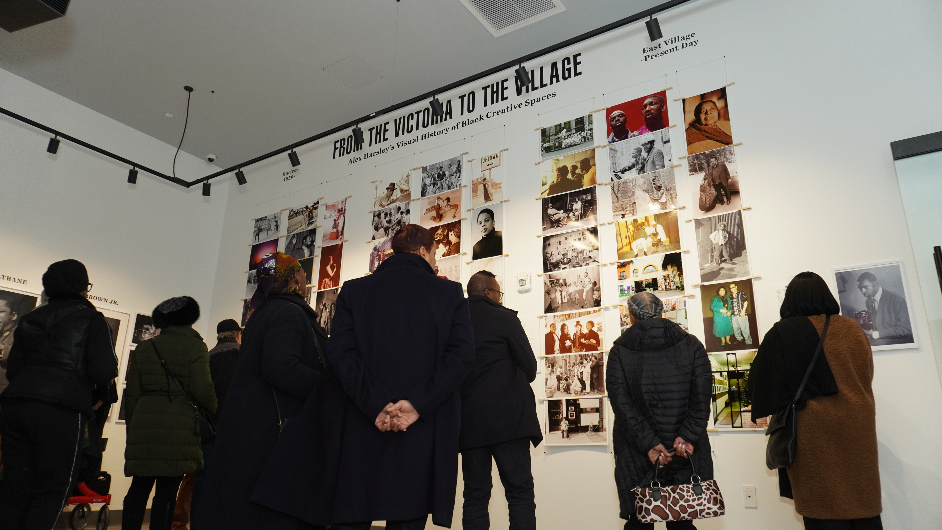 A group of people look at the photos by Alex Harsley.