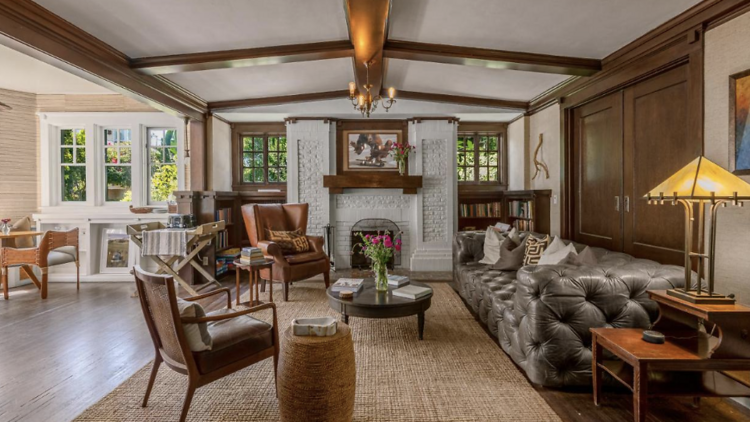 Lounge with fireplace, leather sofa, a woven rug, and high ceilings with exposed beams. 