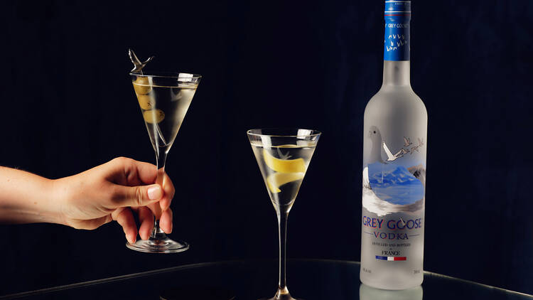 Two Martini cocktails and a bottle of Grey Goose vodka.