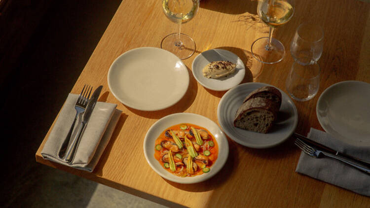Assorted dishes and glasses of white wine on a wooden table.