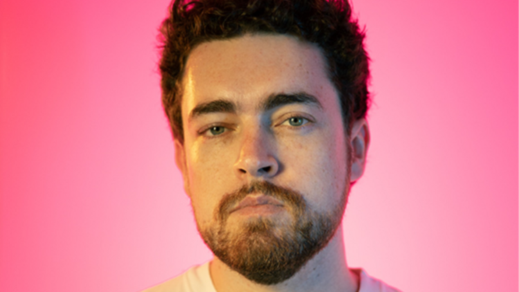 A headshot of Nick White with a candy pink background