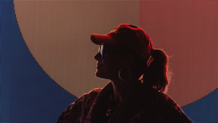 DJ Jnett in shadow in front of a light-up backdrop