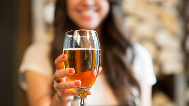 A woman holding a beer in a glass