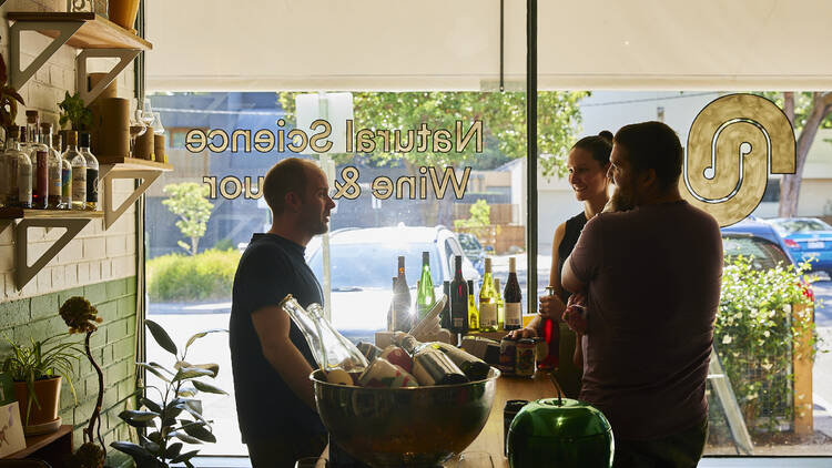 Liquor store staff chatting to customers.