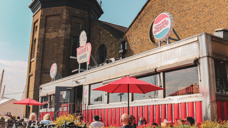 The outside of Fat Boy's Diner with people sat under red umbrellas 