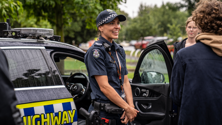 A woman police officer in front of police car 