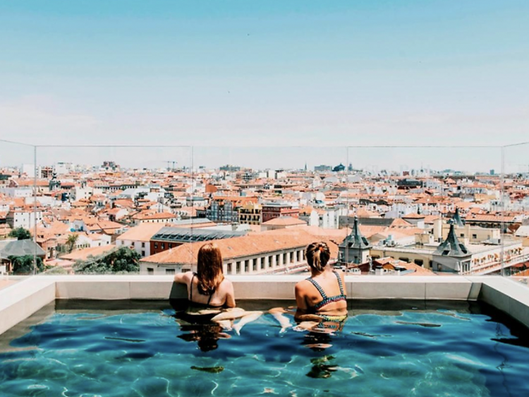 Two women in a rooftop terrace plunge pool overlooking the city.