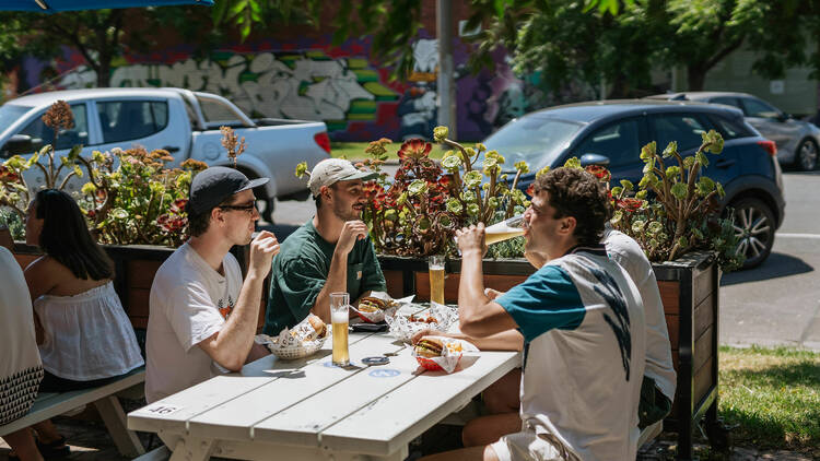 Group of mates enjoying beers in the sun at a brewery.