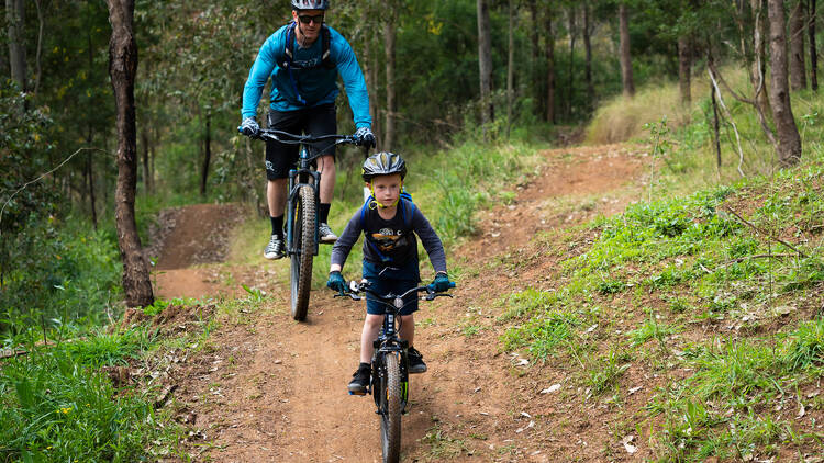 A father and son biking through a park