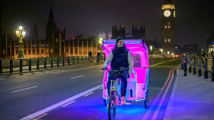 London rickshaw/pedicab driver with Big Ben and the Houses of Parliament