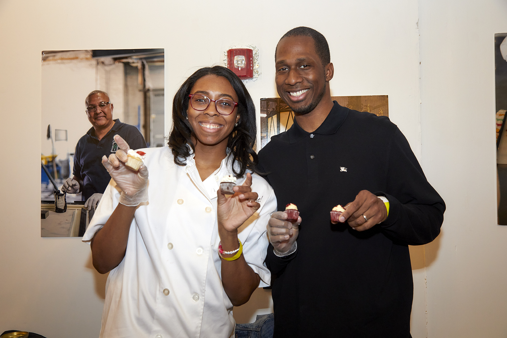 Two people holding a cupcake