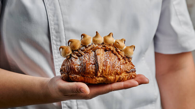 Baker holding Lune's toasted marshmallow cruffin.