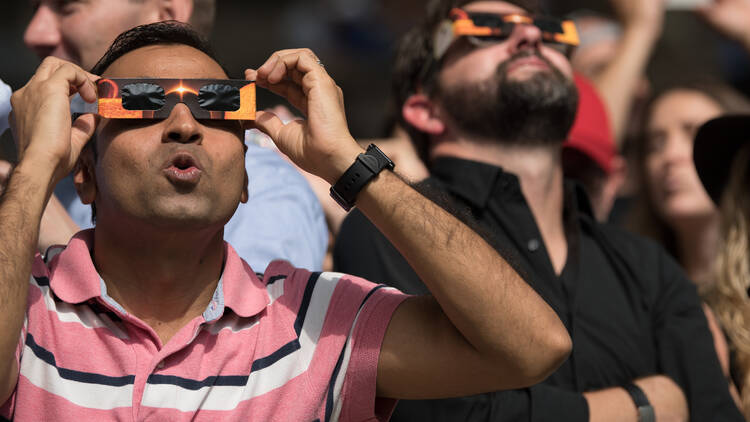 Tourists and locals gaze in awe at the partial solar eclipse in Midtown Manhattan's Bryant Park on August 21, 2017.