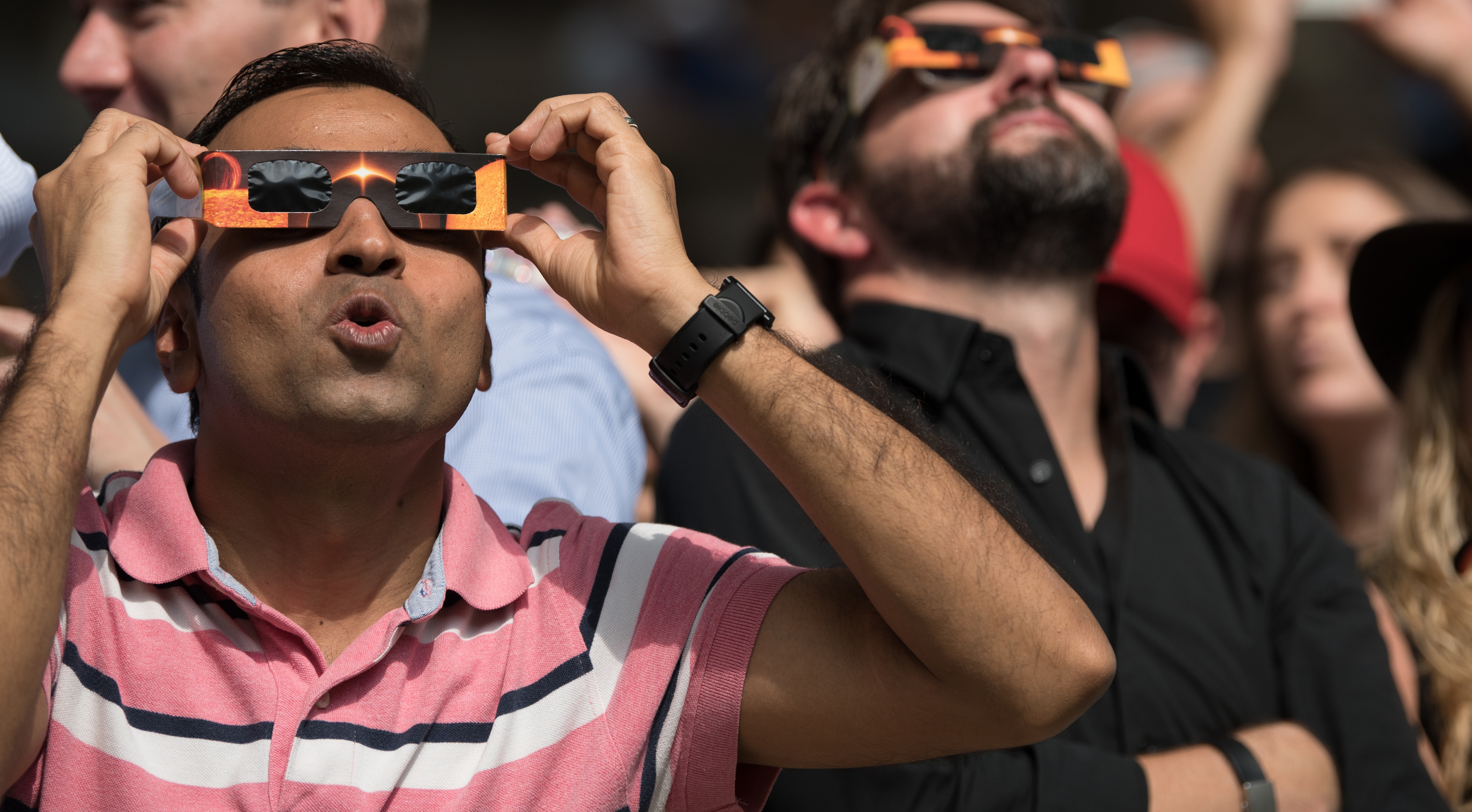 Tourists and locals gaze in awe at the partial solar eclipse in Midtown Manhattan's Bryant Park on August 21, 2017.