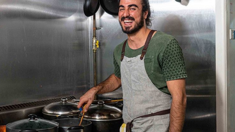 Salamatea owner Hamed Allahyari stirring in a pan in a kitchen.