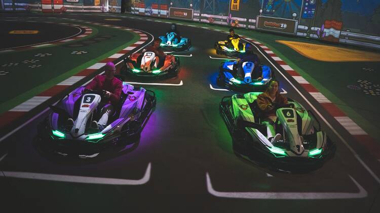 A group of people all in go karts on a track 