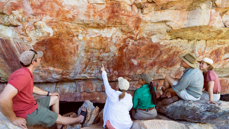 People looking at ancient rock paintings