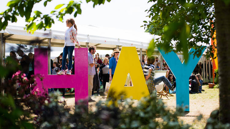 A child sitting on a sign that says Hay