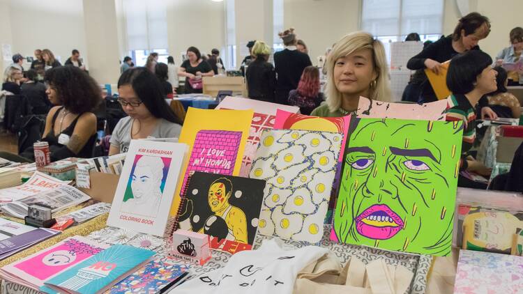 People mill around a table covered with zines.