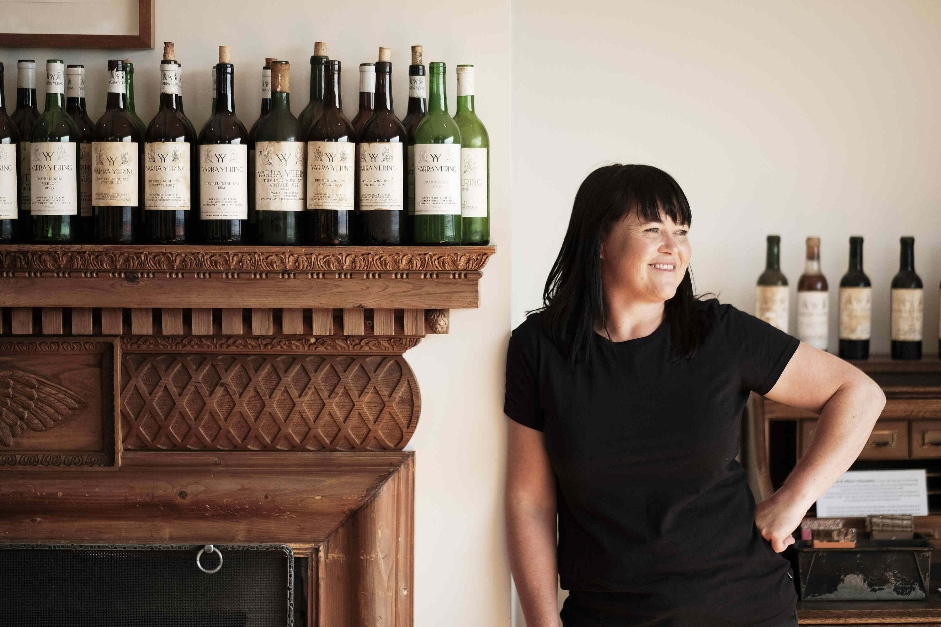 Winemaker Sarah Crowe smiling for the camera with bottles of wine.