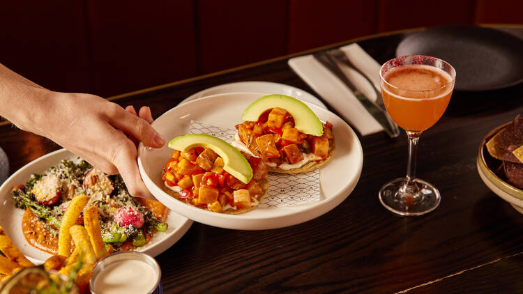 A platter of ceviche tostadas being held above a dark wood table. 
